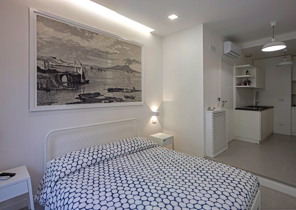 Letto matrimoniale con la cucina sullo sfondo.