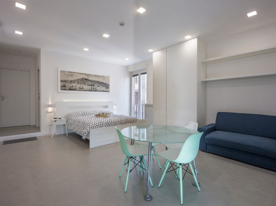 Zona giorno e notte con letto matrimoniale, divano e tavolo da pranzo.